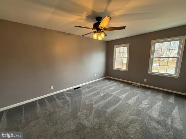 a view of an empty room with window and chandelier fan
