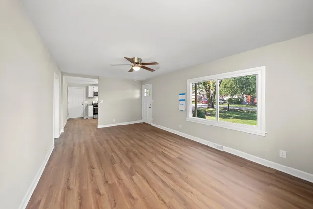a view of empty room with wooden floor and fan
