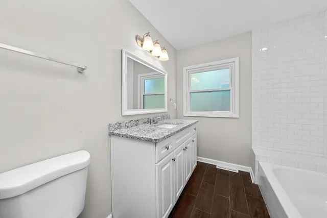 a bathroom with a granite countertop sink a mirror and a toilet