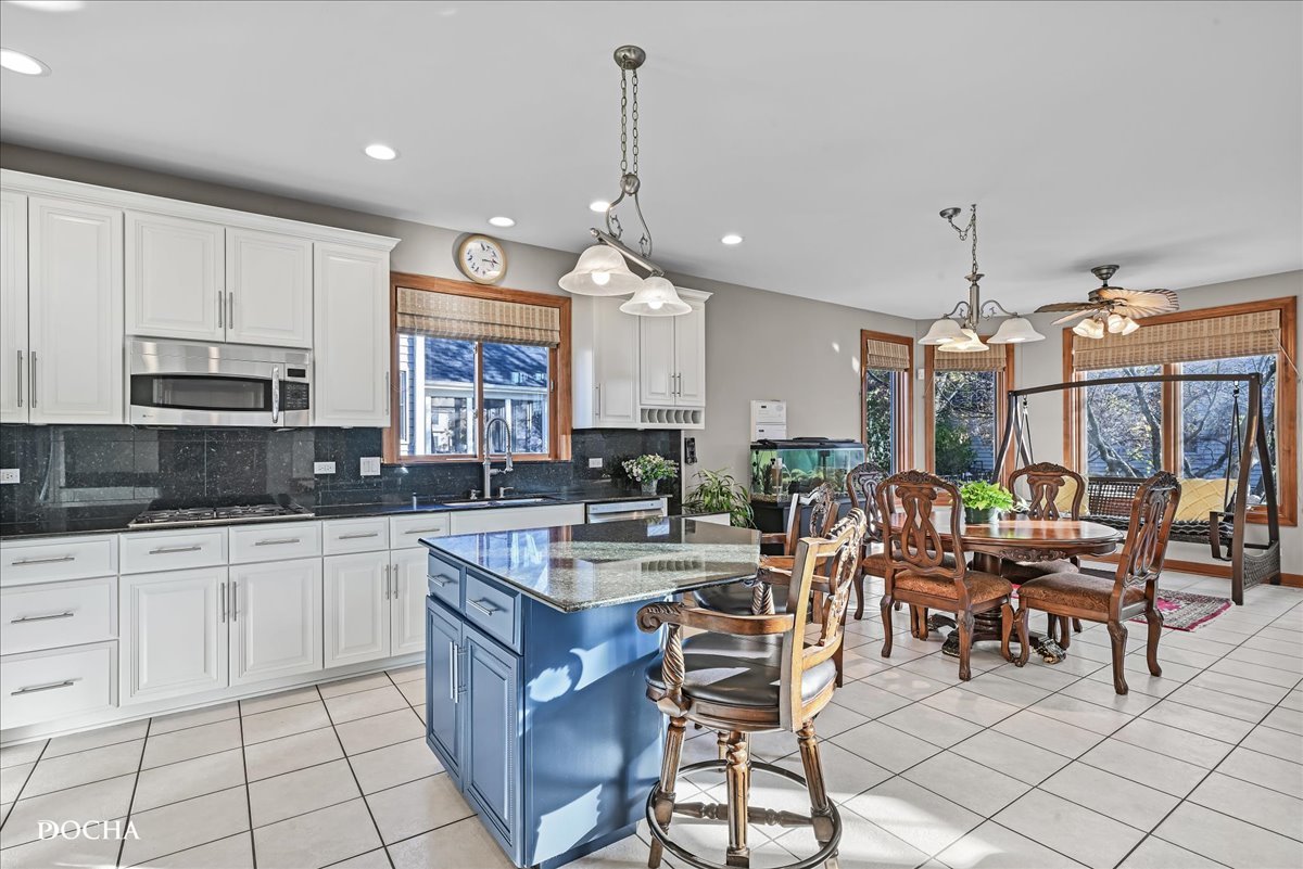 1107 Tuthill Road Naperville, IL 60563 - Photo 15 of 59 a open kitchen with stainless steel appliances granite countertop a stove top oven a sink a dining table and chairs