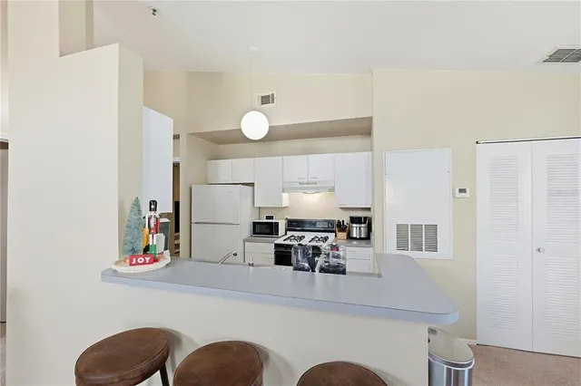 a kitchen with refrigerator and white cabinets