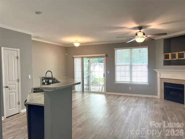a view of an empty room with a kitchen and a window