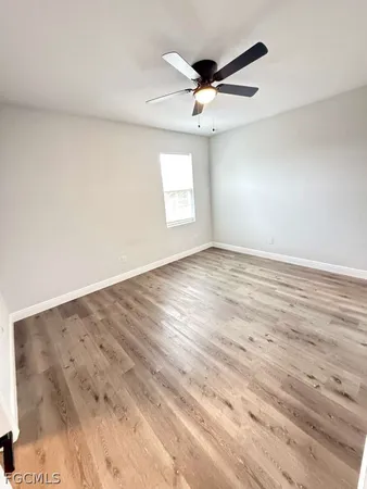 an empty room with wooden floor ceiling fan and windows