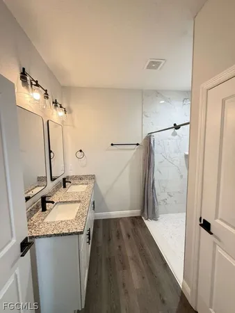 a bathroom with a granite countertop sink a mirror and shower