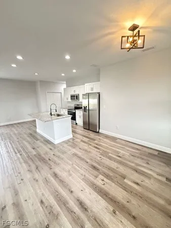 a view of kitchen and empty room with wooden floor