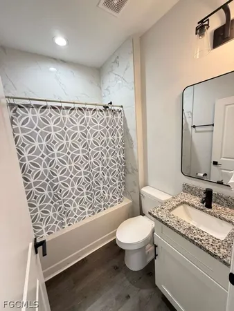 a bathroom with a granite countertop sink toilet and shower