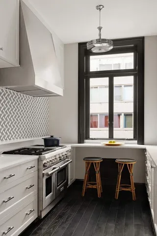 a kitchen with a stove a sink and wooden floor