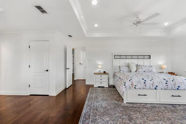 a bedroom with a bed and a dresser with wooden floor