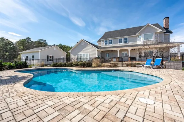 a view of swimming pool that has lawn chairs with plants and lake view