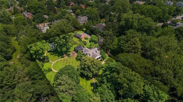 an aerial view of residential house with outdoor space and trees all around