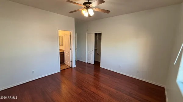 an empty room with wooden floor chandelier fan and closet area