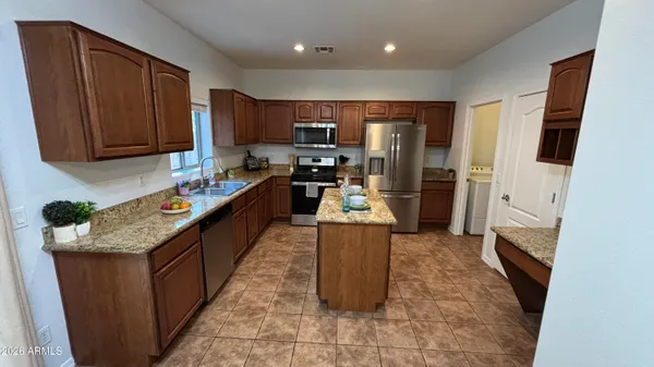 a kitchen with stainless steel appliances granite countertop a stove top oven a sink and a refrigerator