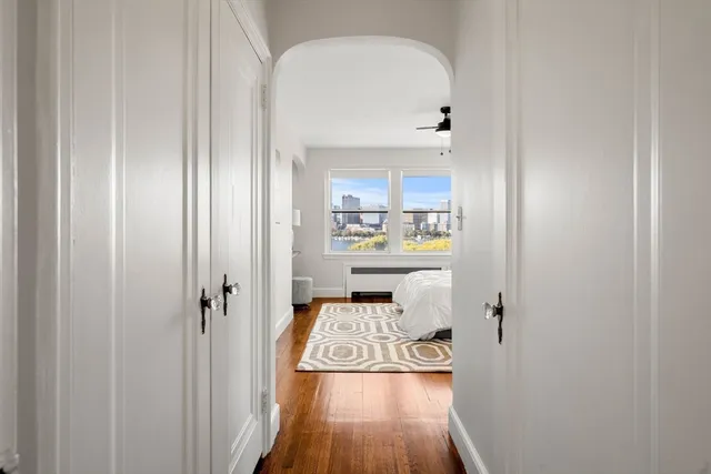 a view of a hallway with wooden floor white cabinet and a refrigerator
