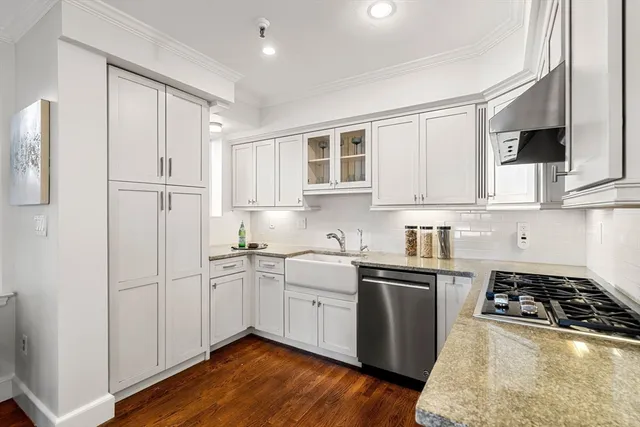 a kitchen with stainless steel appliances white cabinets and a stove top oven