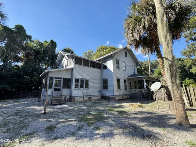 a front view of a house with a garden and tree