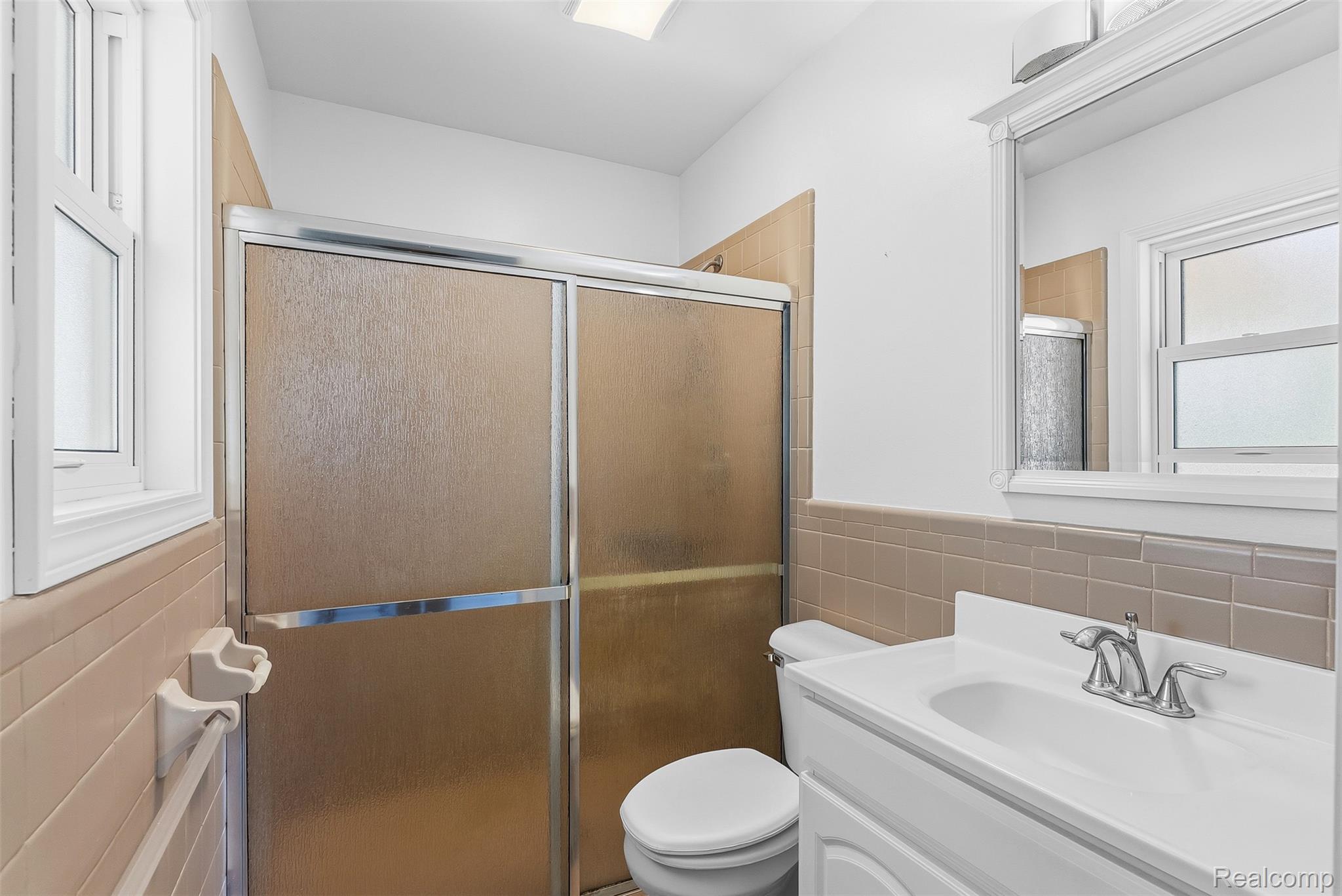 9200 Hickory Ridge Road Holly, MI 48442 - Photo 24 of 33 Bathroom featuring a shower with sliding frosted glass doors, a white toilet, and a vanity with a white sink and chrome faucet