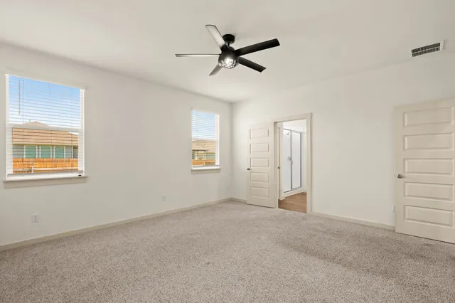 a view of a livingroom with a ceiling fan & windows
