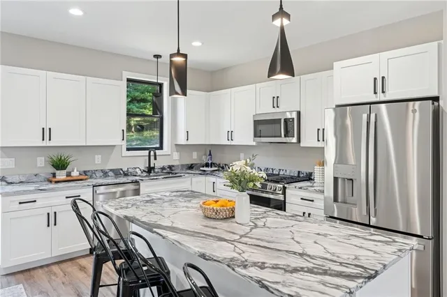 a kitchen with stainless steel appliances a stove a refrigerator a sink a stove a dining table and chairs