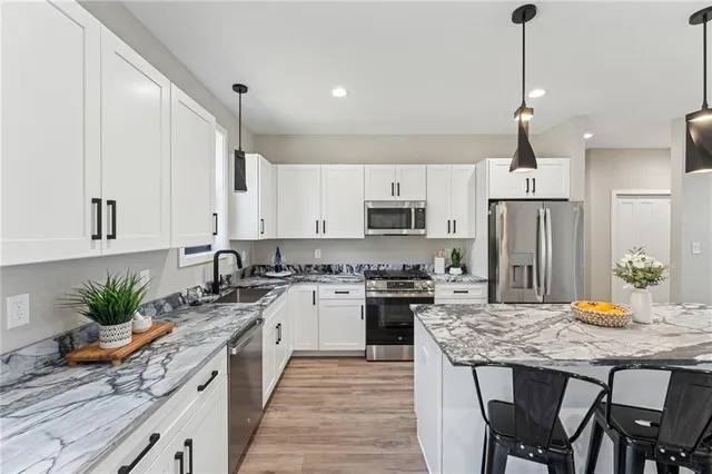 a kitchen with stainless steel appliances granite countertop sink stove top oven and refrigerator