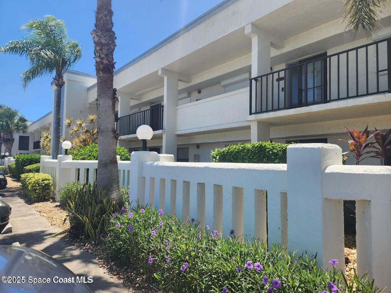 3165 North Atlantic Avenue, Unit C105 Cocoa Beach, FL 32931 - Photo 2 of 10 a front view of a house with porch and flowers