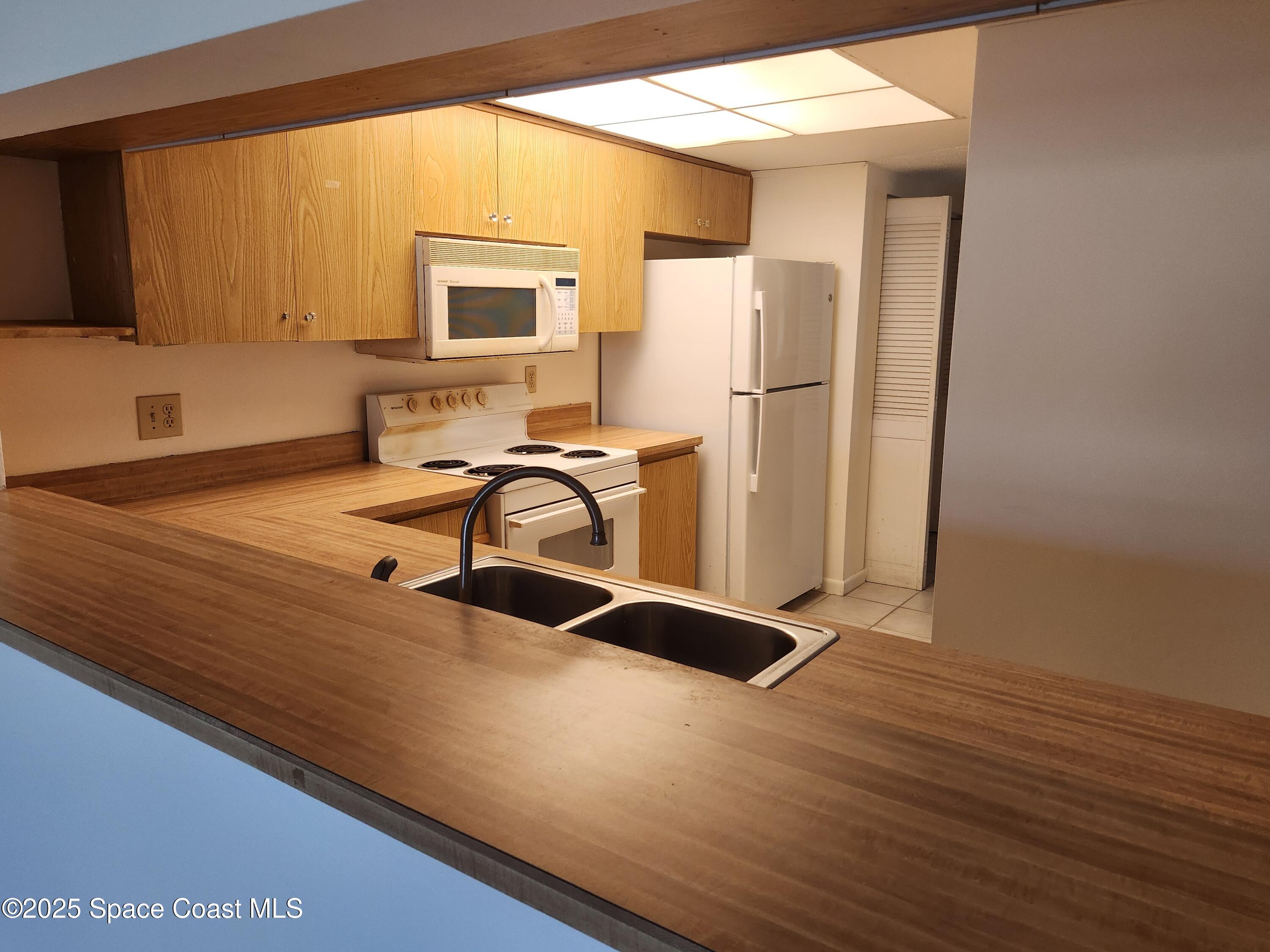 3165 North Atlantic Avenue, Unit C105 Cocoa Beach, FL 32931 - Photo 3 of 10 a view of a kitchen with a sink and a refrigerator