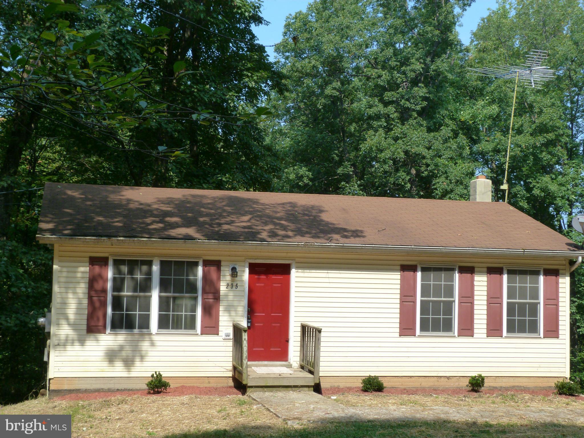 a front view of a house with a garden and tree