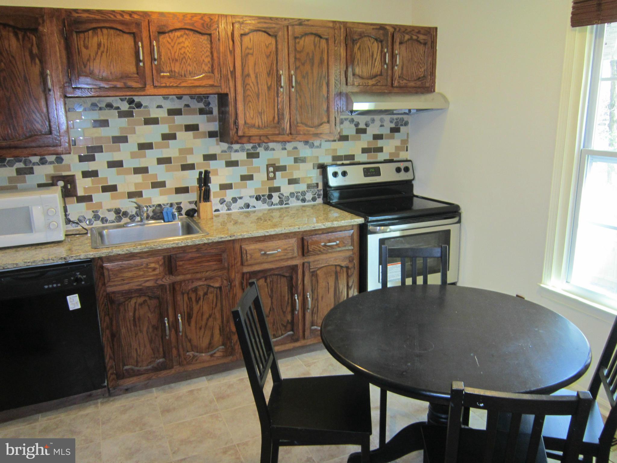 8587 Tyrolean Way Springfield, VA 22153 - Photo 19 of 30 a kitchen with a sink a stove a table and chairs