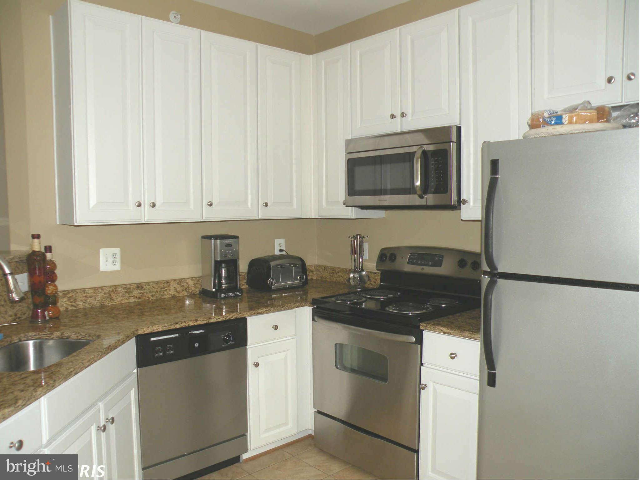 12705 Found Stone Road, Unit 301 Germantown, MD 20876 - Photo 12 of 21 a kitchen with granite countertop white cabinets sink and stainless steel appliances