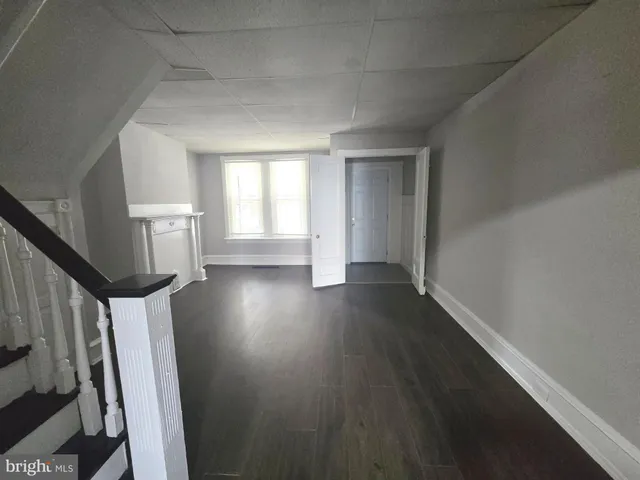 a view of an empty room with wooden floor and stairs