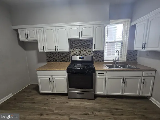 a kitchen with stainless steel appliances a stove a sink and white cabinets