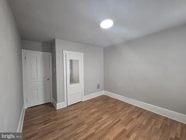 a view of an empty room with wooden floor and closet