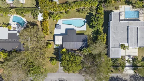 an aerial view of residential house with outdoor space and trees all around