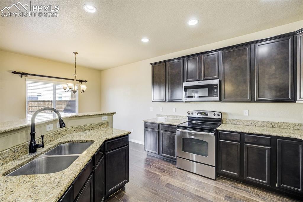 Undisclosed Address Colorado Springs, CO 80925 - Photo 14 of 45 a kitchen with kitchen island granite countertop a sink wooden cabinets and stainless steel appliances