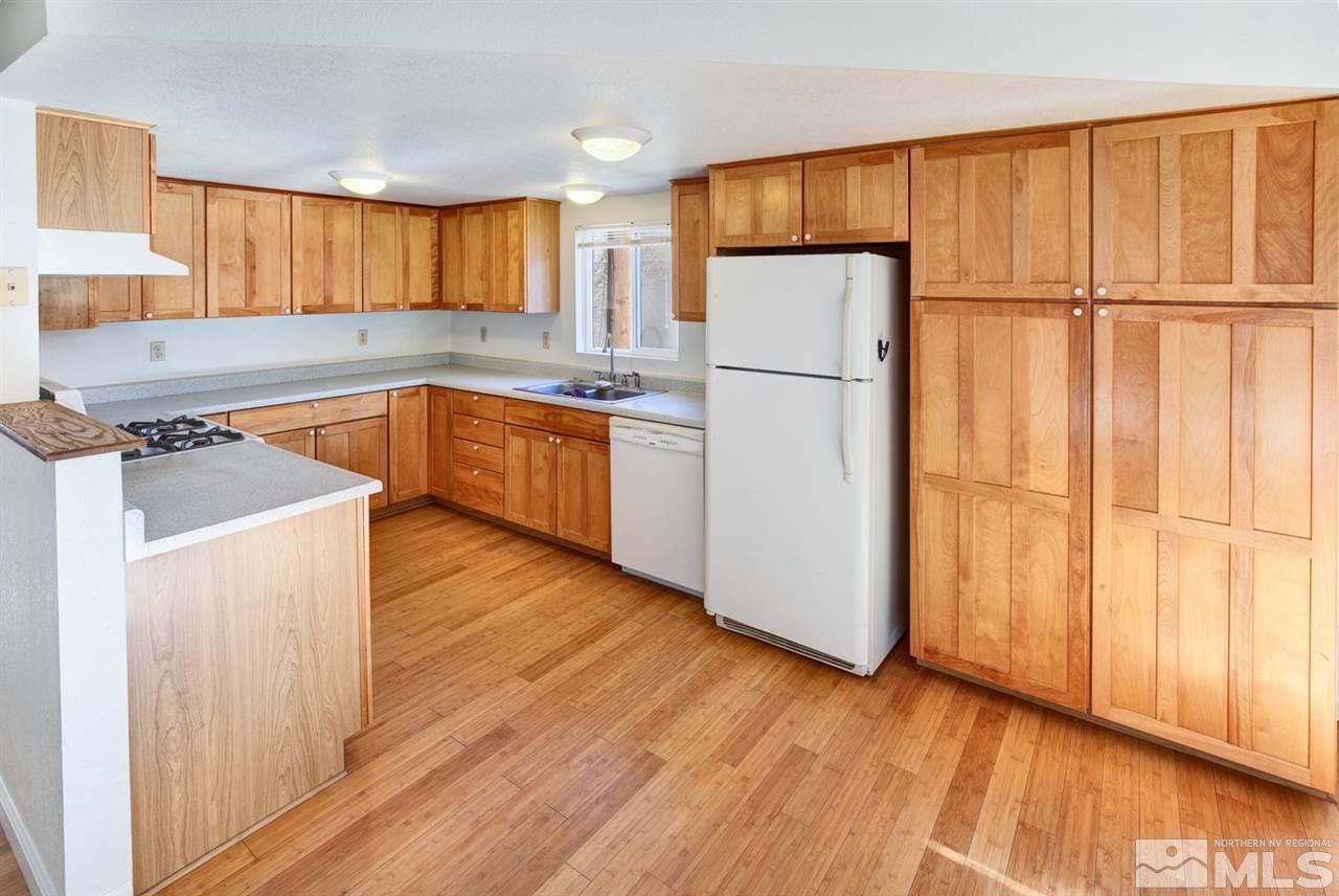 4320 Reno Highway Fallon, NV 89406 - Photo 4 of 28 a kitchen with a refrigerator a stove top oven a counter space and wooden floor