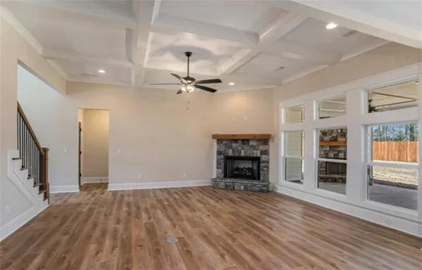 an empty room with wooden floor fireplace and windows
