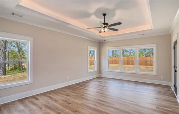 an empty room with wooden floor fan and windows