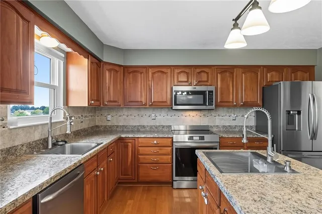 a kitchen with stainless steel appliances granite countertop a sink stove microwave and refrigerator
