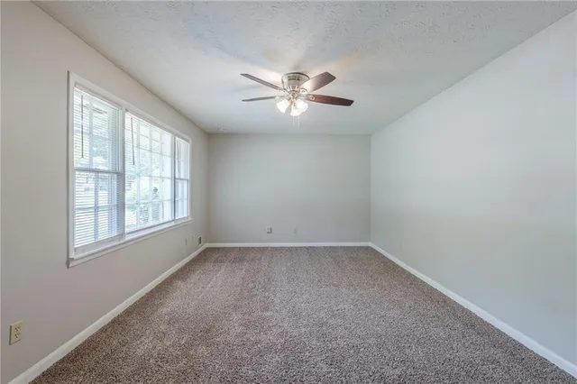 an empty room with a window and a fan