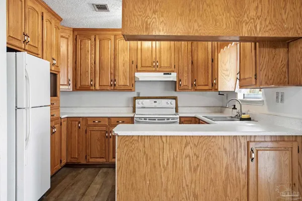 a kitchen with stainless steel appliances granite countertop a refrigerator a sink dishwasher and wooden cabinets with wooden floor