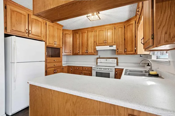 a kitchen with stainless steel appliances granite countertop a refrigerator a sink dishwasher a stove with wooden cabinets and floor
