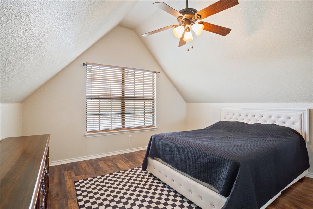 8600 Five Wells Road Rogers, TX 76569 - Photo 19 of 40 Bedroom featuring dark wood-type flooring, lofted ceiling, a textured ceiling, and ceiling fan