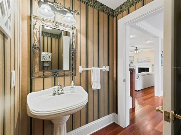 a view of a hallway with wooden floor and a bathroom