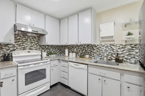 a kitchen with white cabinets and sink