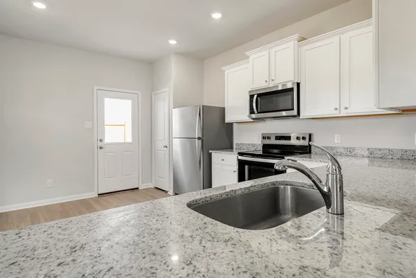 a kitchen with stainless steel appliances granite countertop a sink a microwave a refrigerator and grey cabinets