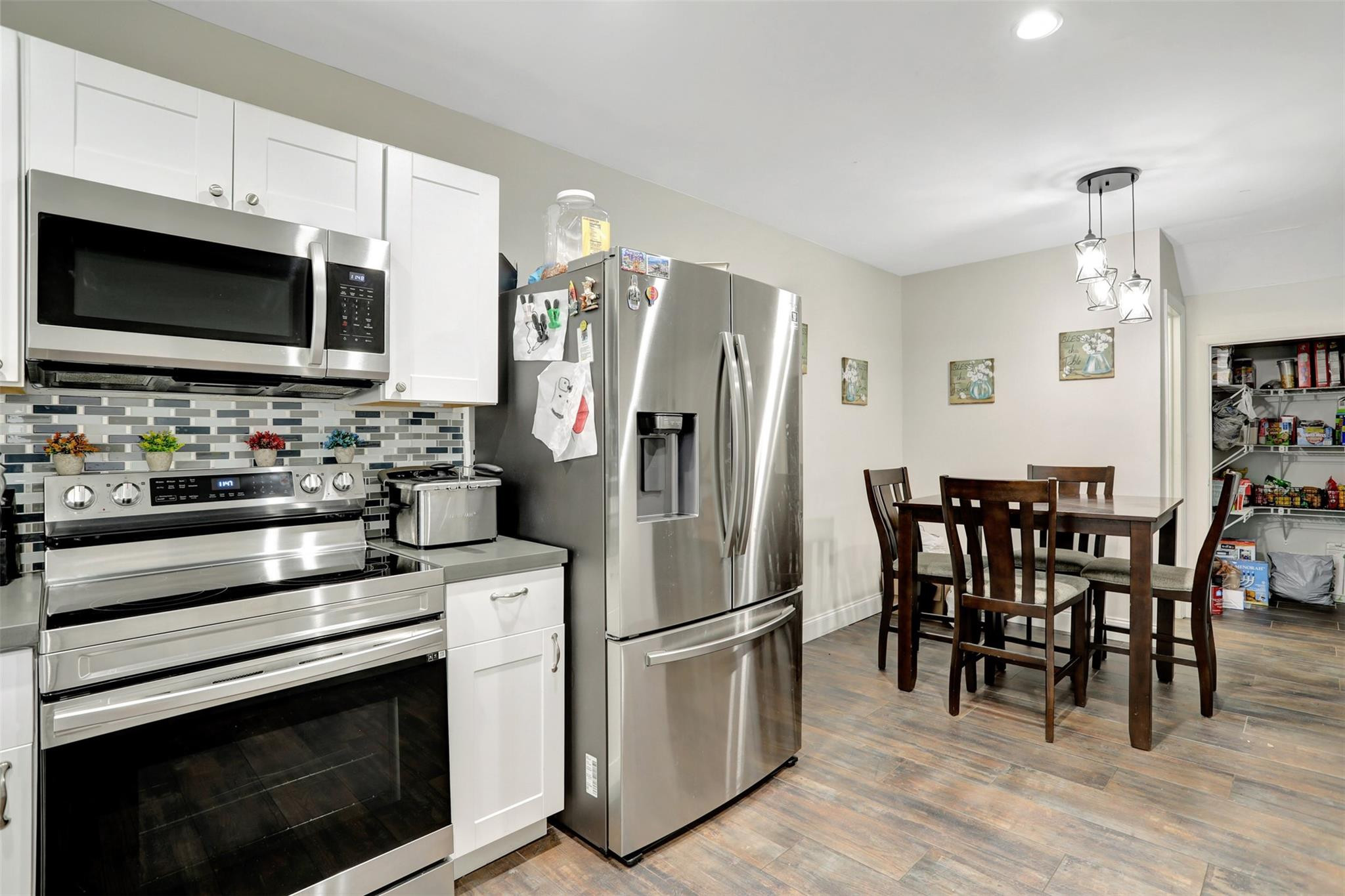 9430 Southwest 61st Way, Unit A Boca Raton, FL 33428 - Photo 6 of 32 a kitchen with stainless steel appliances a stove a microwave a refrigerator a stove a dining table and chairs with wooden floor