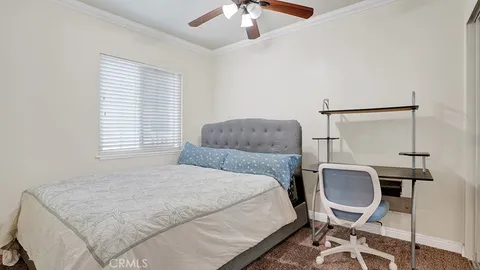 a bedroom with a bed windows and chair