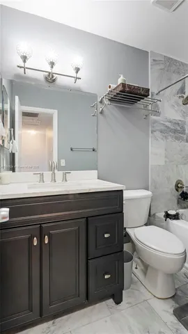 a bathroom with a granite countertop toilet sink and mirror