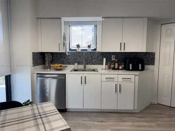 a kitchen with white cabinets and sink