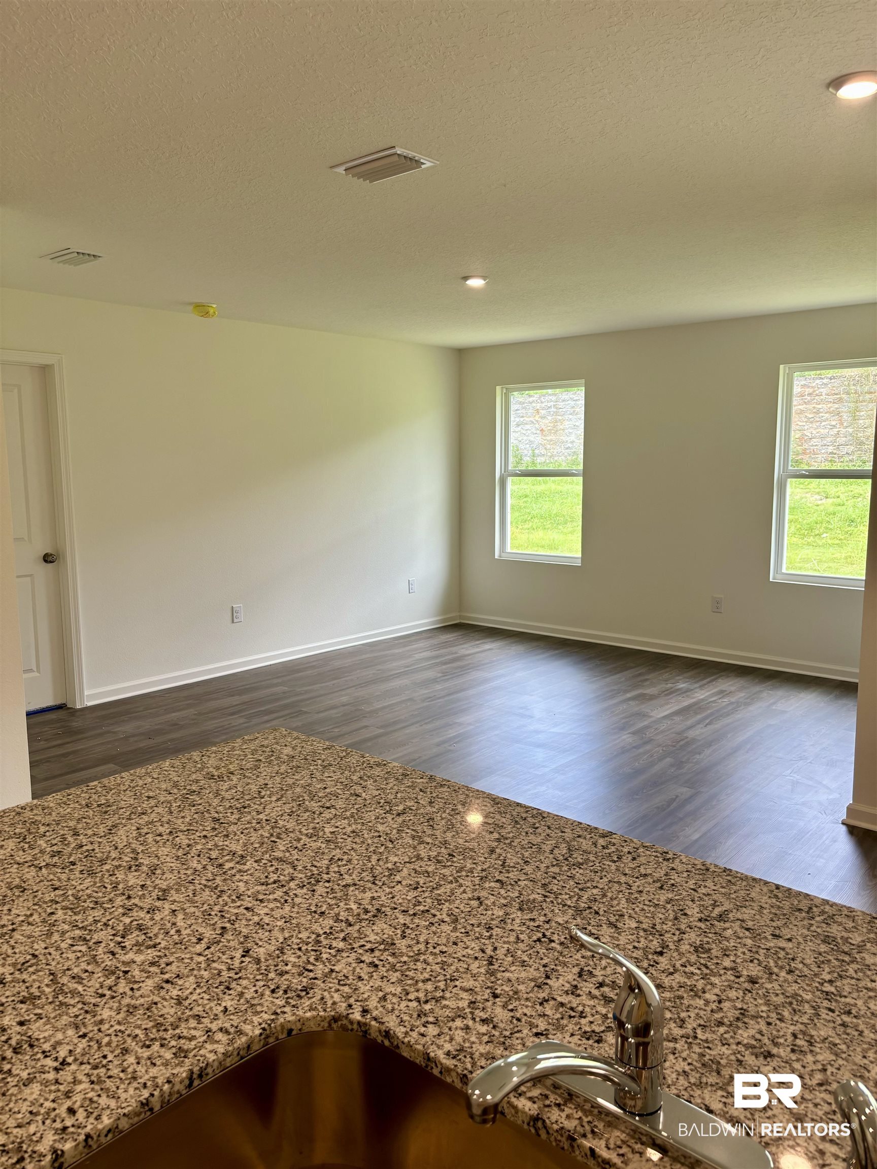 21641 Sutherland Circle Fairhope, AL 36532 - Photo 5 of 17 Empty room featuring plenty of natural light, dark wood-type flooring, and a textured ceiling