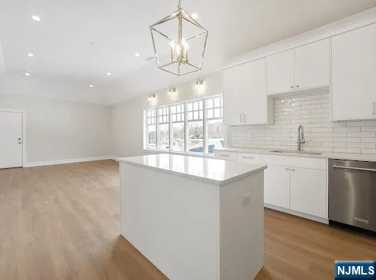 a kitchen that has a lot of white cabinets and wooden floor